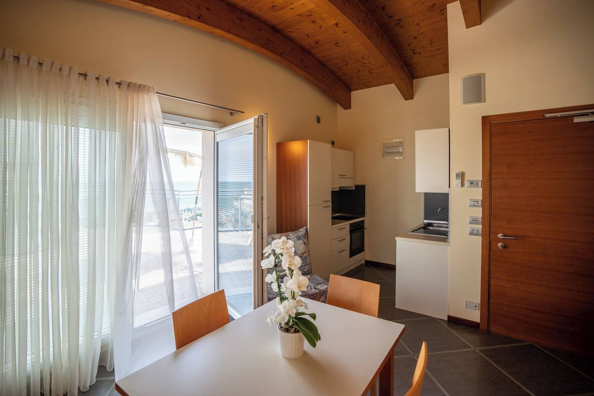 Una cocina compacta con comedor, techo de madera y vistas al exterior.