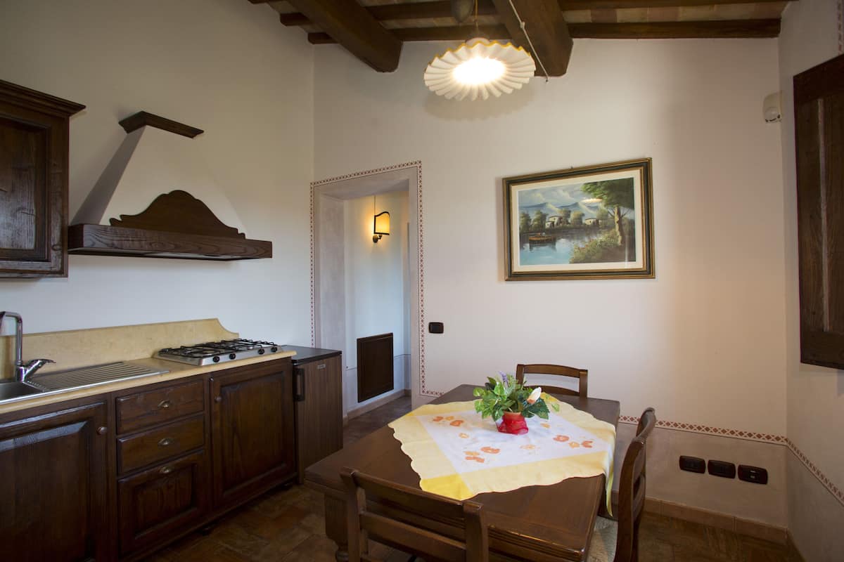 A kitchen with wooden cabinets, a gas stove, and a dining table with chairs.