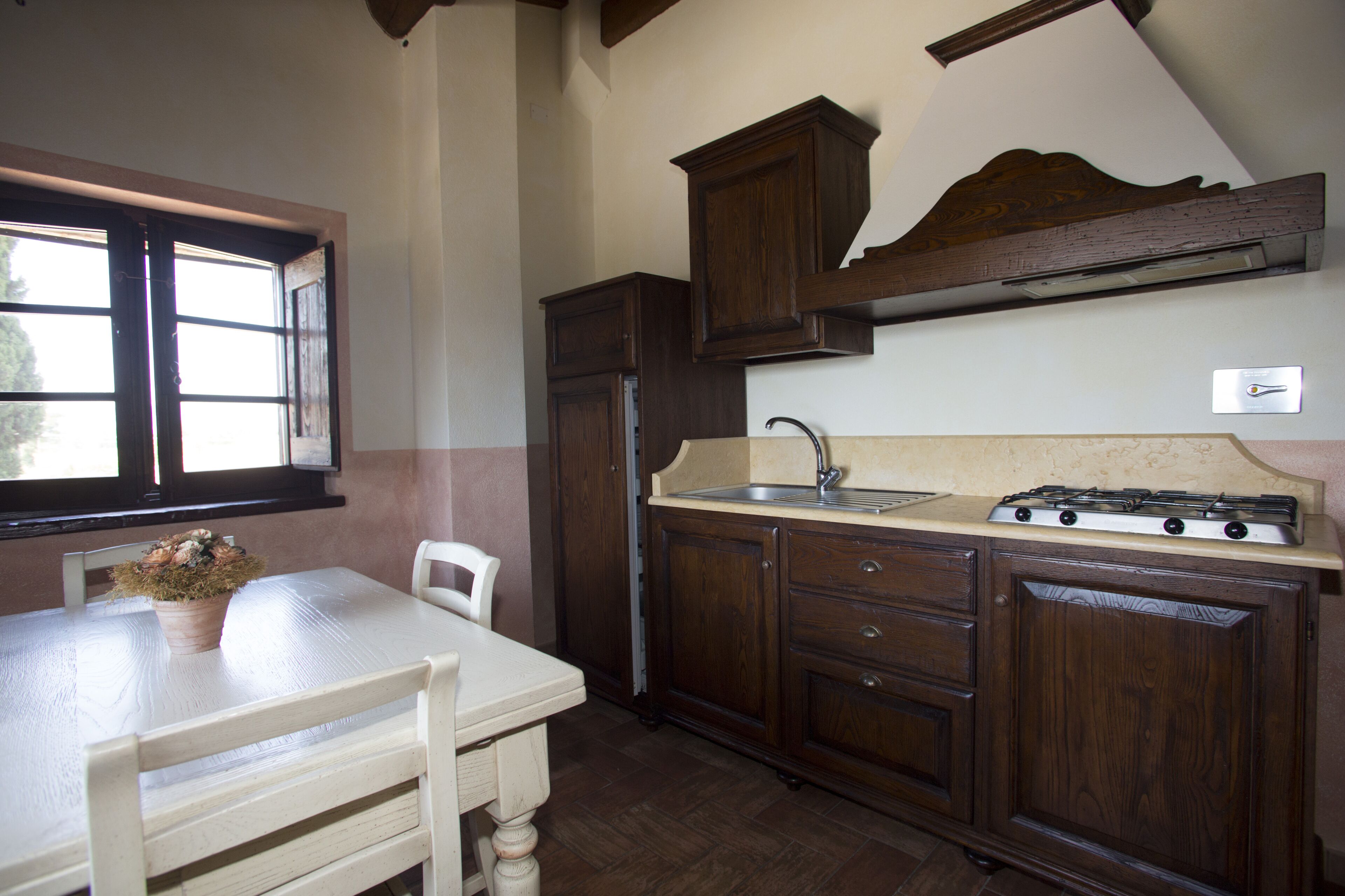 A kitchen with wooden cabinets, a white table, and a window.