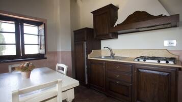A kitchen with wooden cabinets, a white table, and a window.