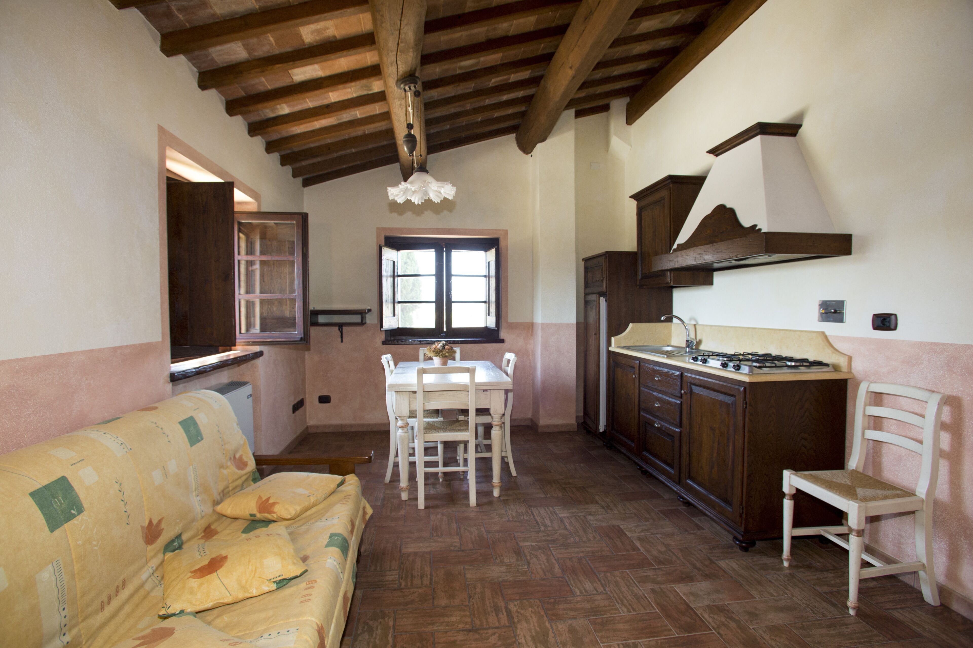 A cozy kitchen with wooden cabinets, a dining table, and a sofa.