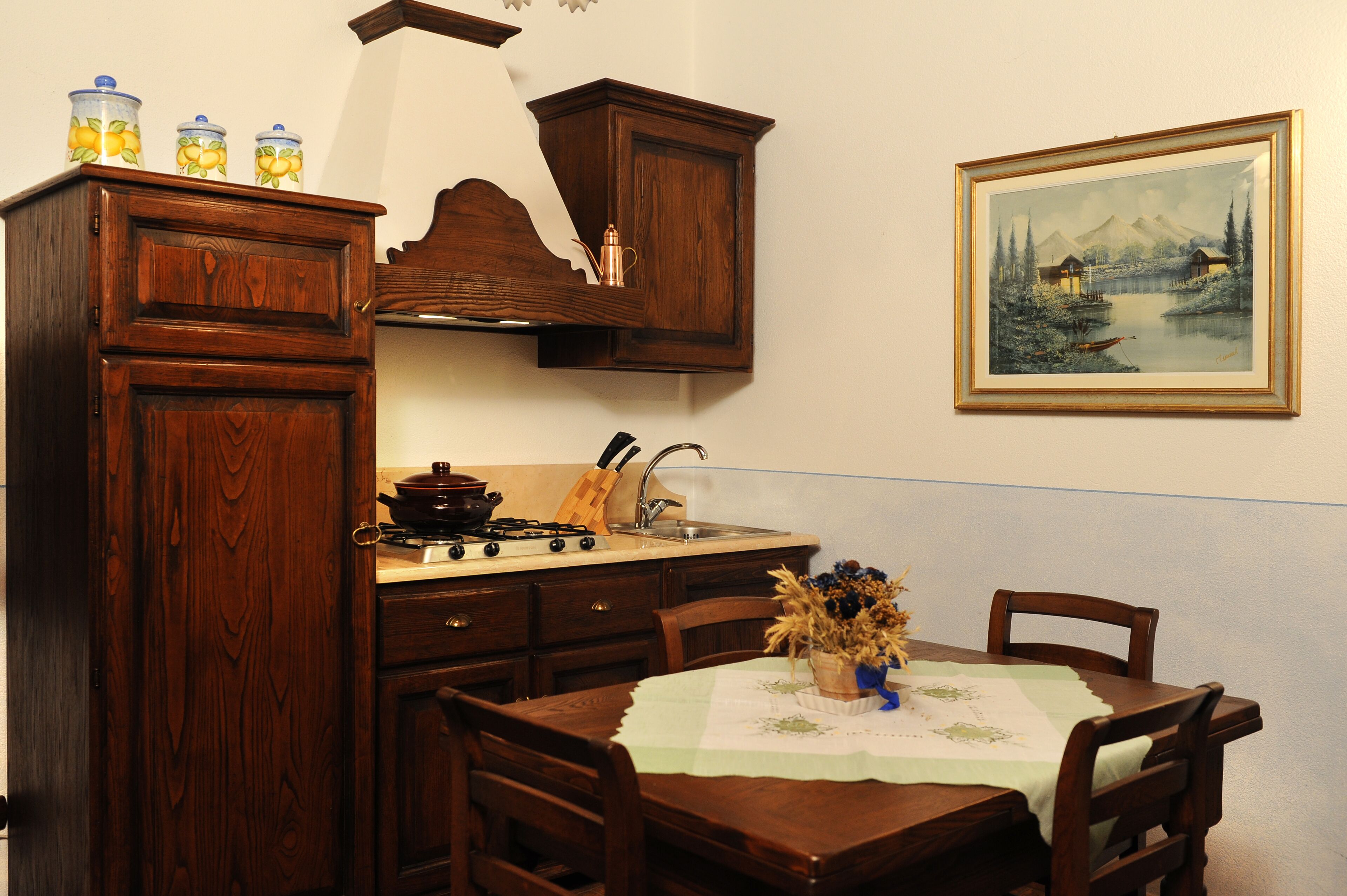 Una cocina con armarios de madera, una estufa y una mesa de comedor con sillas.