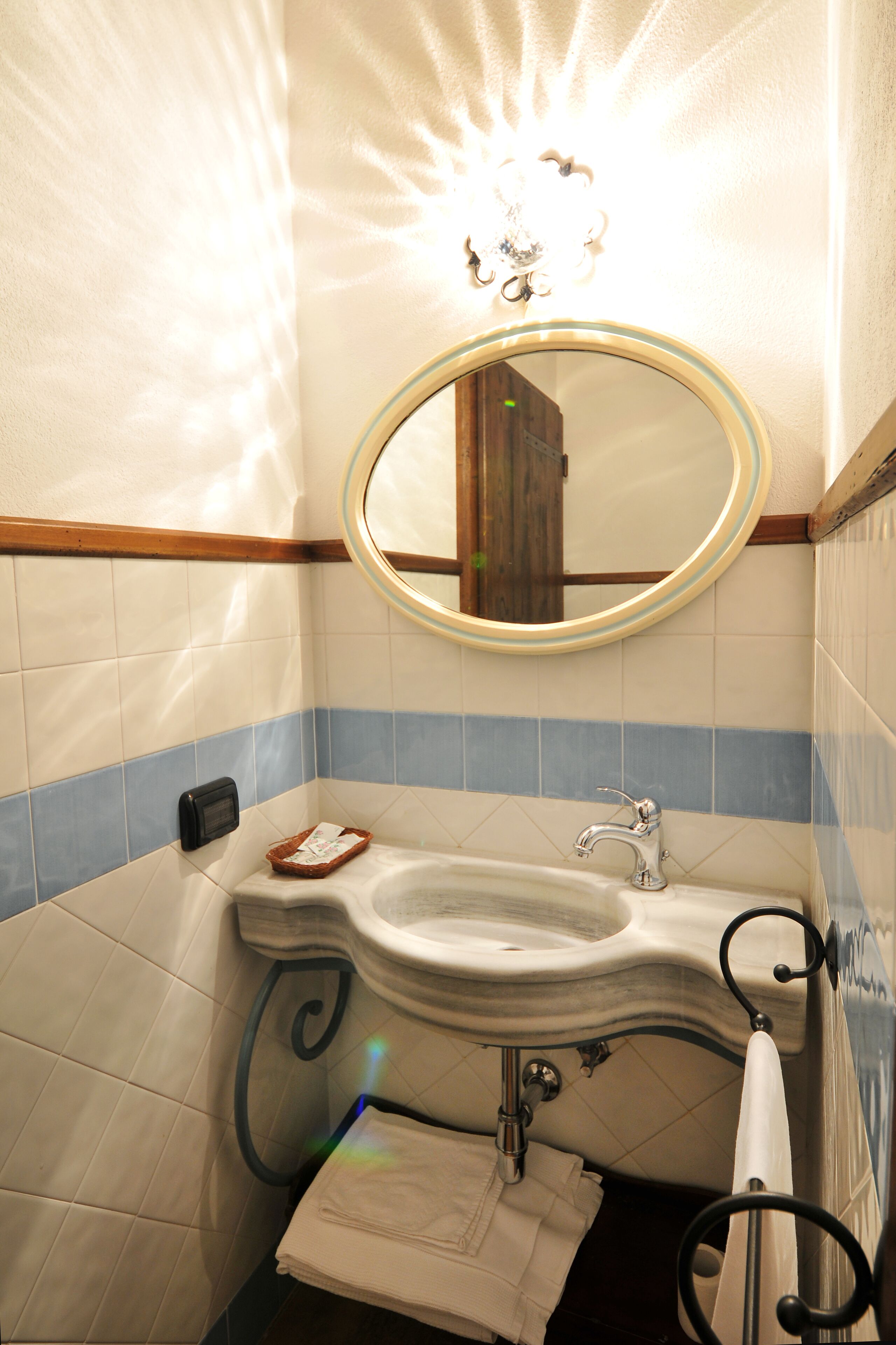 Ein Badezimmer mit Waschbecken, Spiegel, Handtuchhalter und einer Lampenleiste.