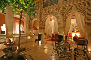 Un amplio patio interior con una fuente, zona de estar y una mesa de comedor.