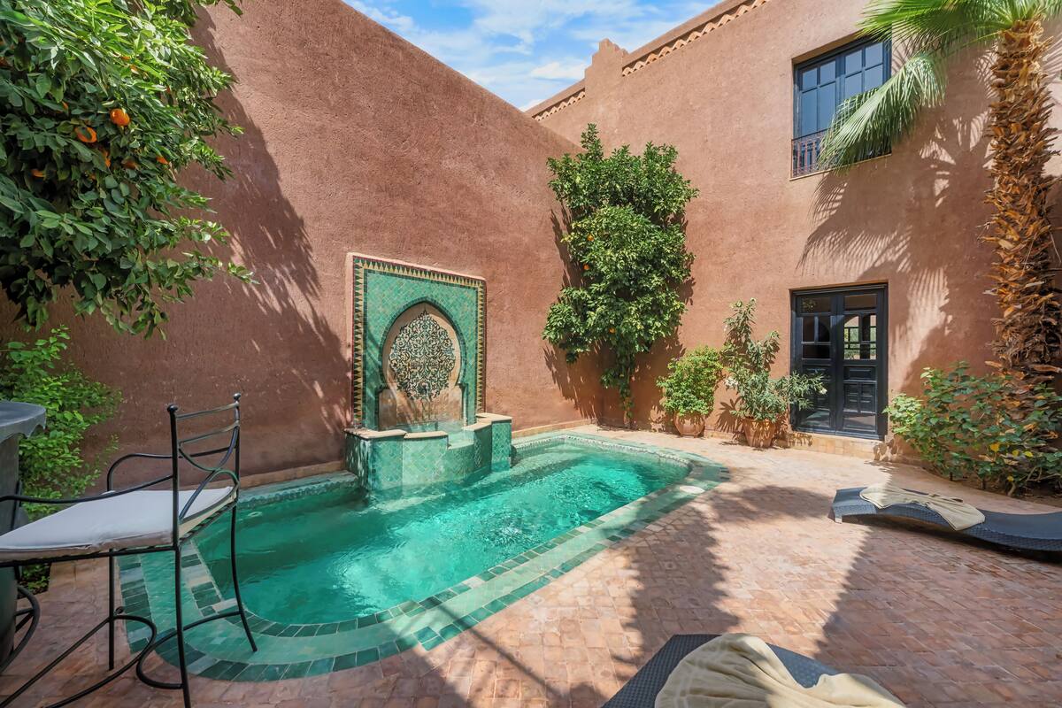 Une cour avec une piscine, une chaise et une fontaine décorative.