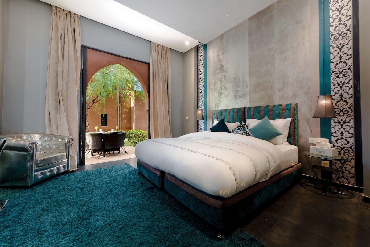 Une chambre moderne avec un grand lit, un canapé et une vue sur un espace extérieur.