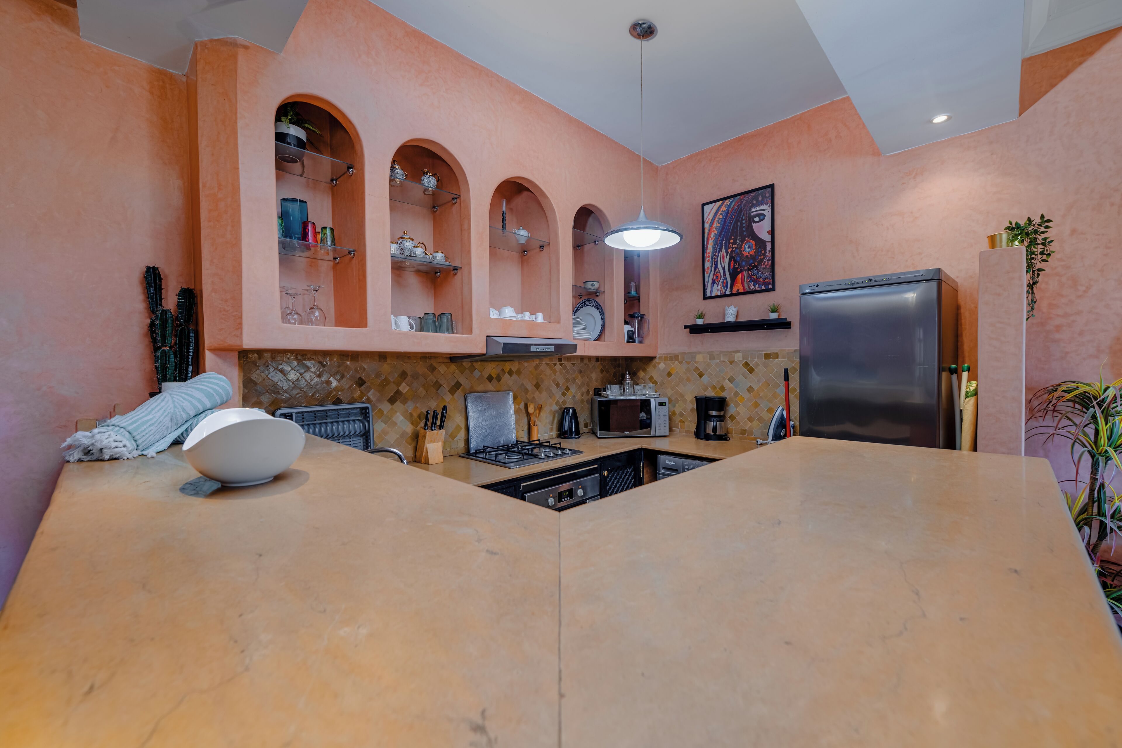 A kitchen with a central island, built-in shelves, and a refrigerator.