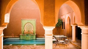 Una piscina interior amb una font, envoltada d'arcs i columnes.