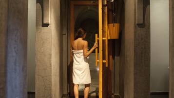 A woman in a towel walking through a hallway with a wooden ladder and a hanging basket.