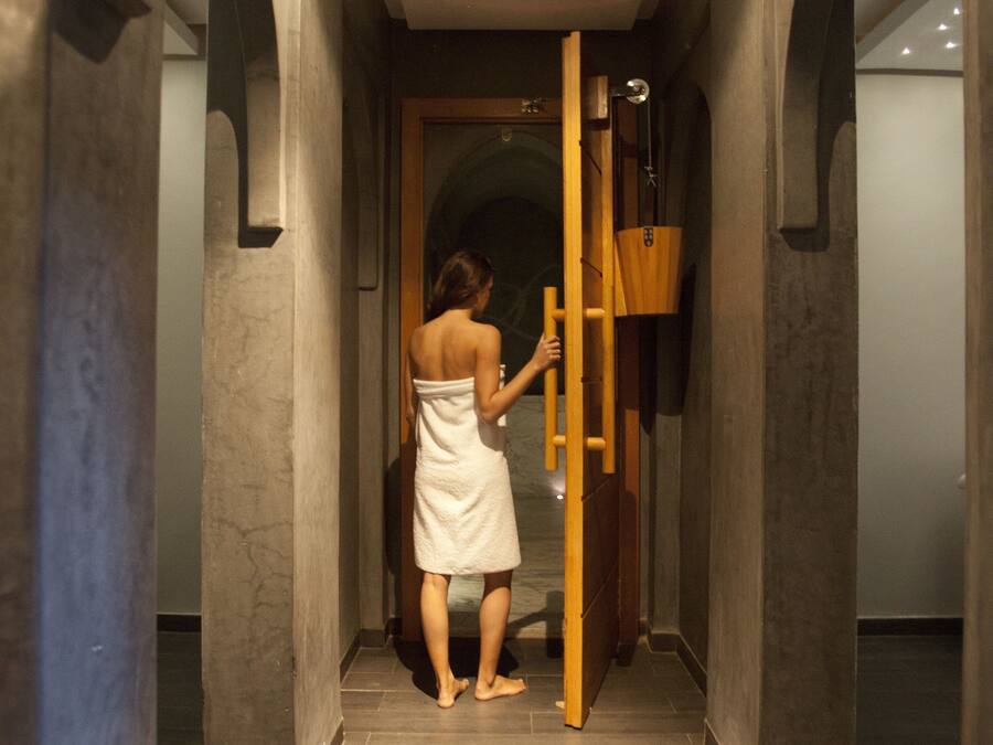 A woman in a towel walking through a hallway with a wooden ladder and a hanging basket.