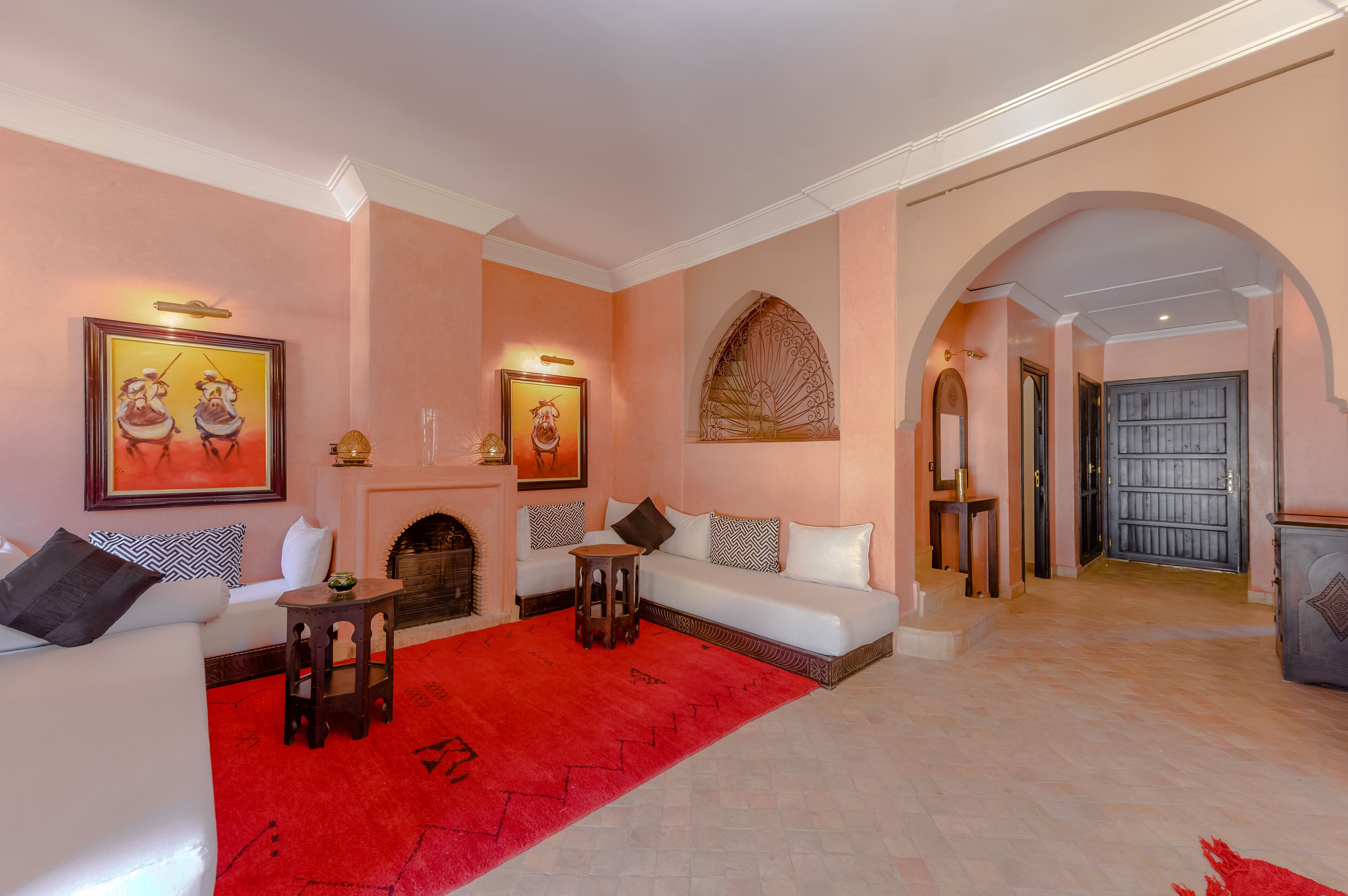 Un salon spacieux avec un canapé blanc, un tapis rouge et une cheminée.