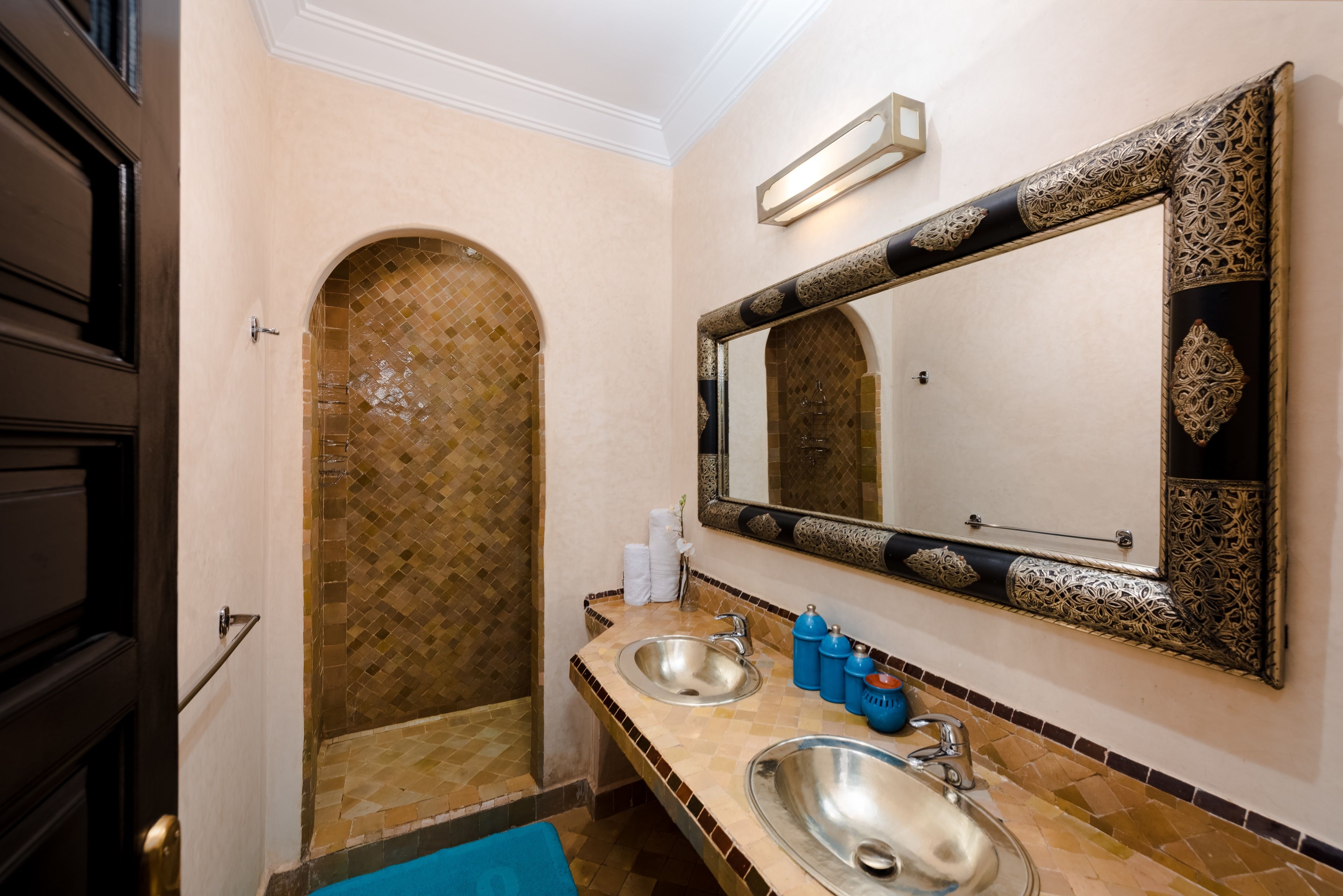 A bathroom with two sinks, a large mirror, and a shower area with mosaic tile.