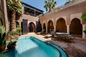 A pool area with a tiled edge, lounge chairs, and a table. - Résidence Dar Lamia Marrakech (Marrakech)