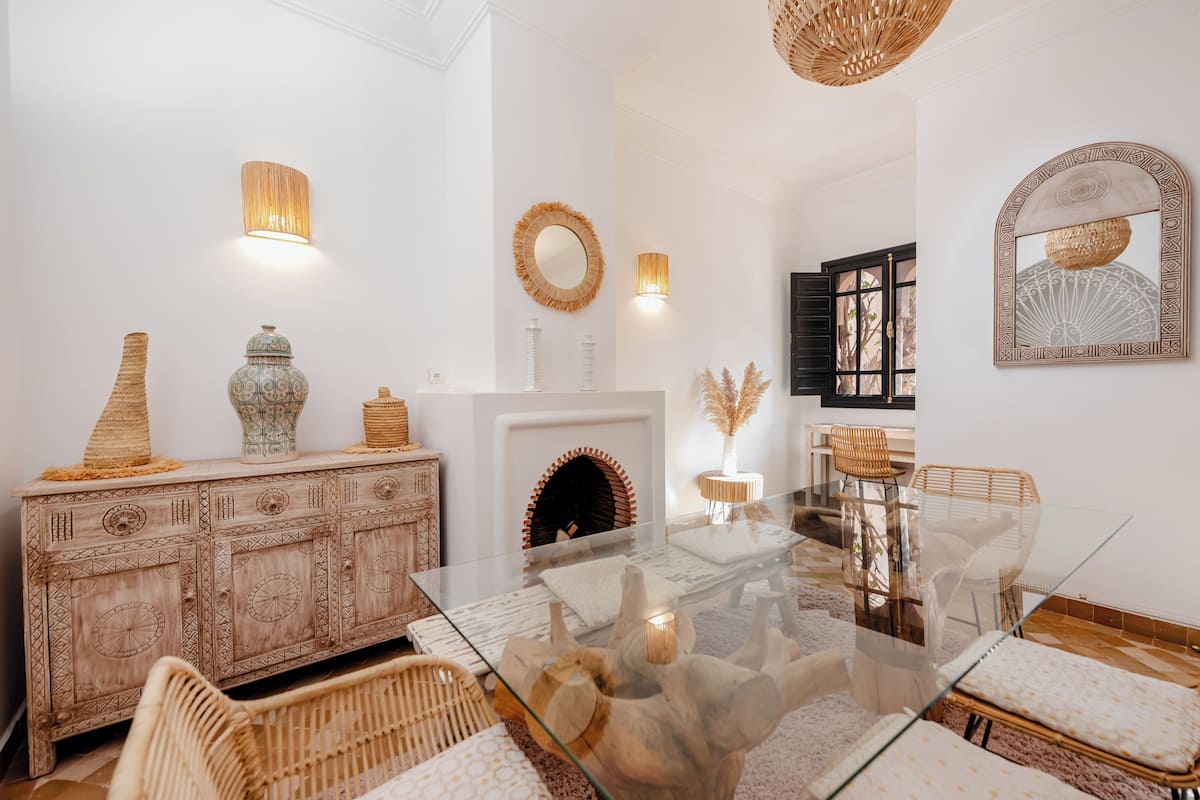 Un salon moderne avec une table basse en verre, des meubles en osier et des objets décoratifs disposés sur un meuble.