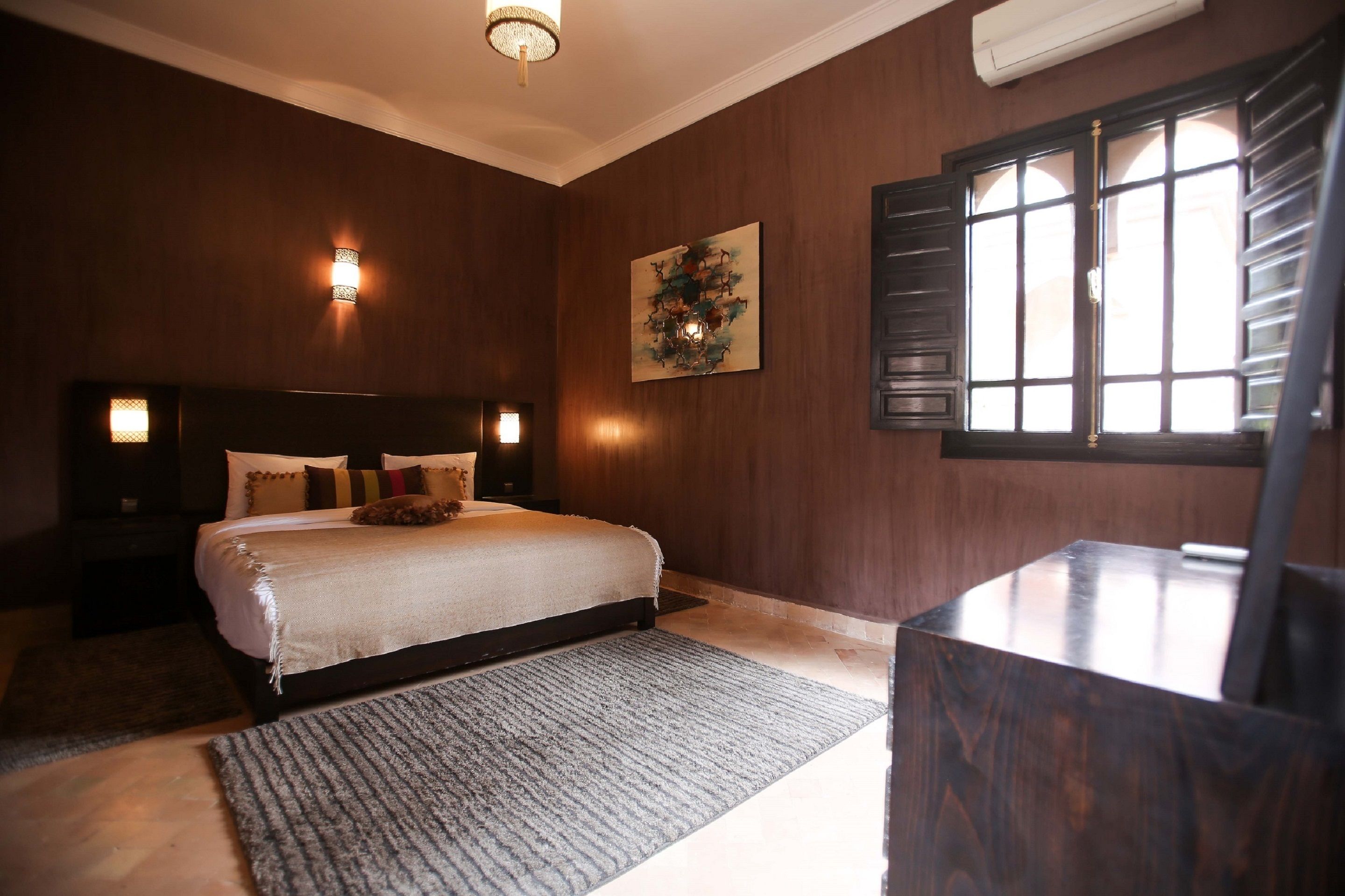 Ein Schlafzimmer mit einem großen Bett, einem Bettrahmen mit Beleuchtung, einem Gemälde und einem Fenster mit Fensterläden.