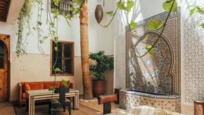 A traditional Moroccan interior with a sofa, table, and potted plants. - Riad Anya (Marrakech)