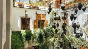 A courtyard with hanging lanterns, a wooden door, and a tiled roof. - Riad Anya (Marrakech)