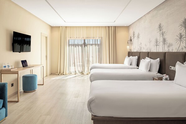 A hotel room with two beds, a desk with a laptop, a TV, and a large window with sheer curtains. - Red Hotel (Marrakech)
