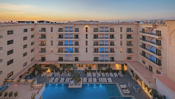 Un hotel amb nombroses terrasses, una piscina central i zones d'estar a l'aire lliure.