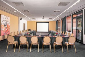 A conference room with a large table, multiple chairs, a projector screen, and a large window with curtains. - Red Hotel (Marrakech)