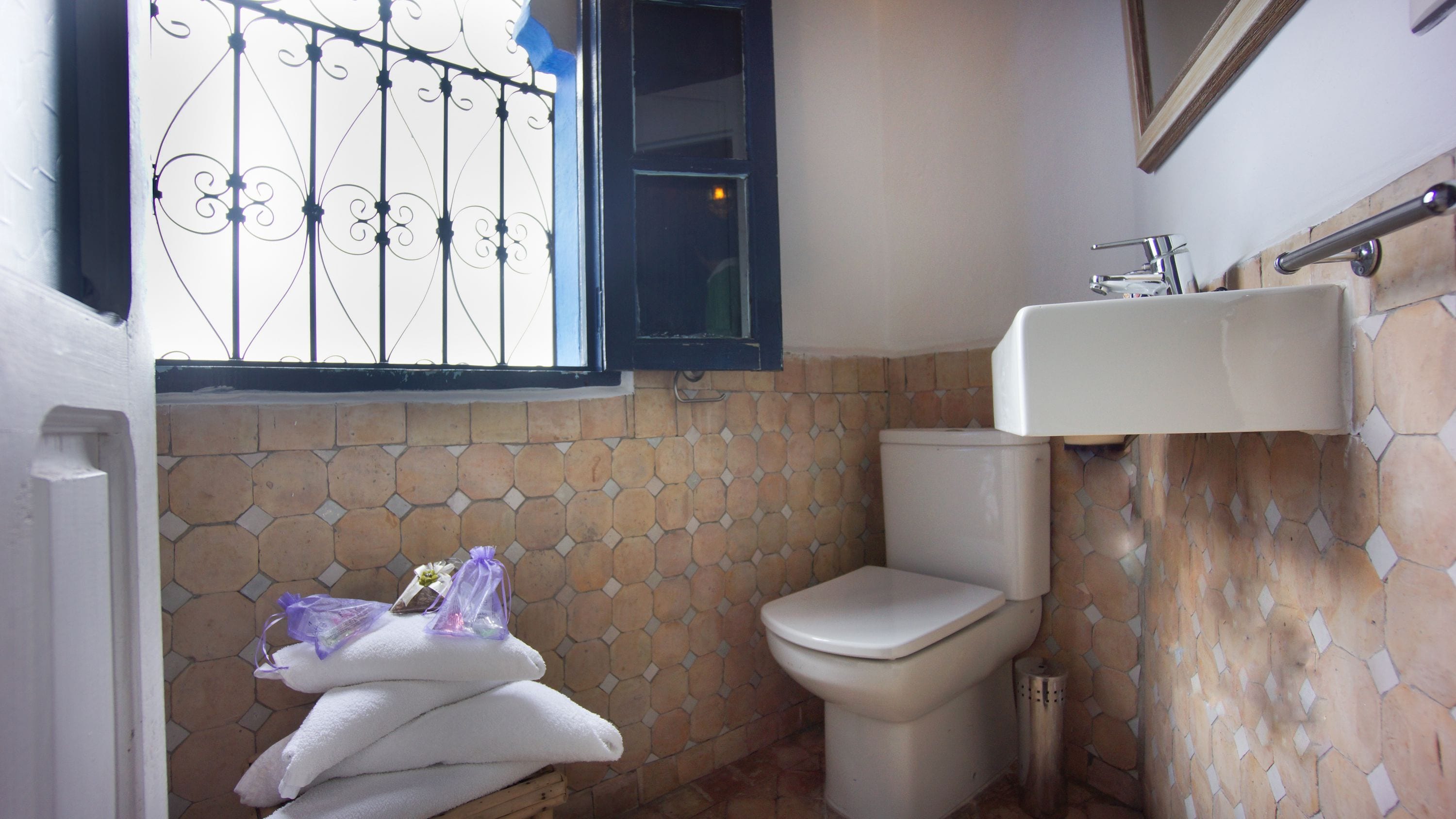 A bathroom with a toilet, a sink, and a window with metal bars.