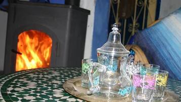 A table with a glass pitcher and four glasses, a tiled floor, and a fire in the background.