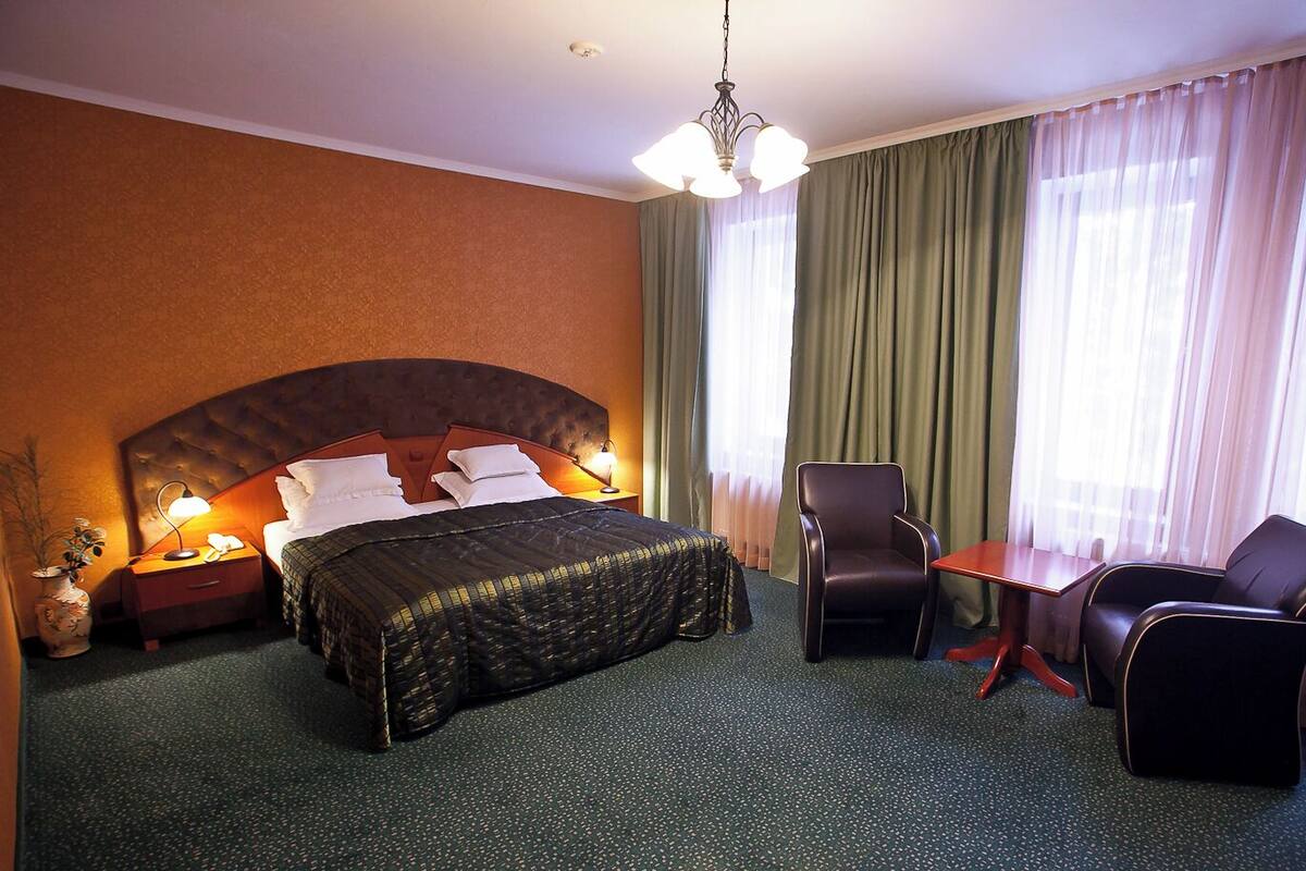 Une chambre d’hôtel avec un grand lit, un bureau, deux chaises, une table de chevet et un vase avec des fleurs.