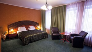 Une chambre d’hôtel avec un grand lit, un bureau, deux chaises, une table de chevet et un vase avec des fleurs.