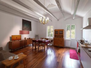 A spacious room with a dining area, kitchen, and a large window.