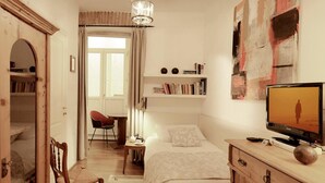 A bedroom with a bed, a desk, a chair, a television, and a bookshelf.