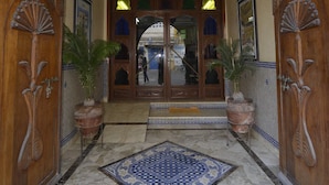 An entrance with a wooden archway, a tiled floor, and two potted plants. - Essaouira Wind Palace (Essaouira)