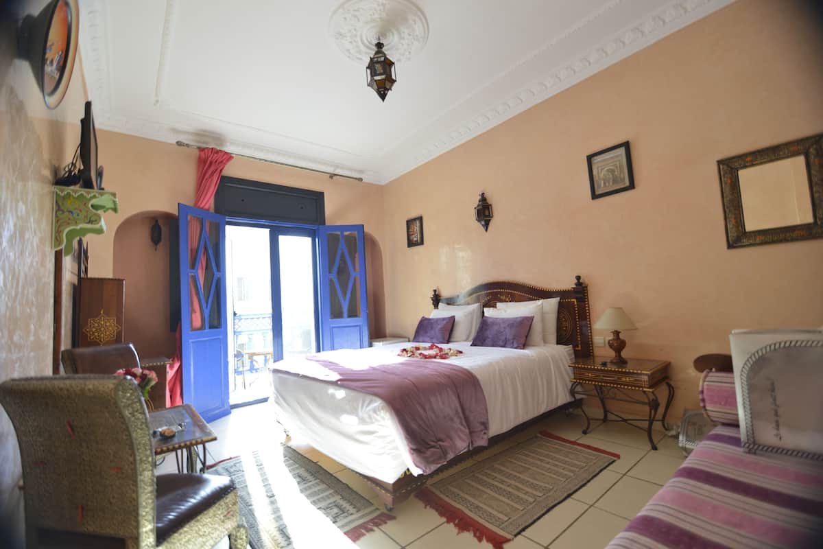 A bedroom with a bed, a chair, a table, and a lamp.