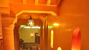 A corridor with ornate columns, a chandelier, and wall-mounted lights. - Essaouira Wind Palace (Essaouira)