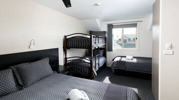 A hotel room with a bunk bed, a single bed, and a window with a view.