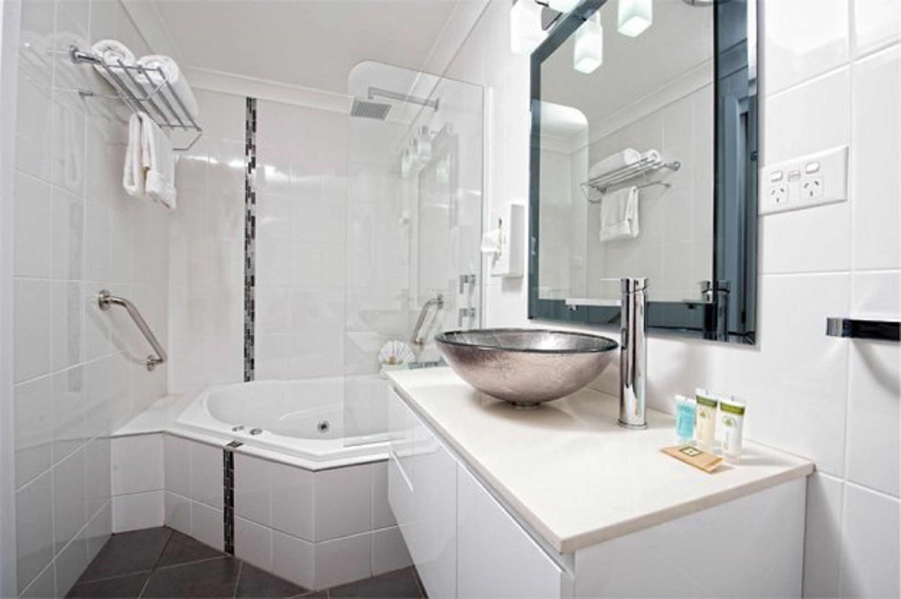 A modern bathroom with a glass-enclosed shower, a freestanding bathtub, and a large mirror above the sink.