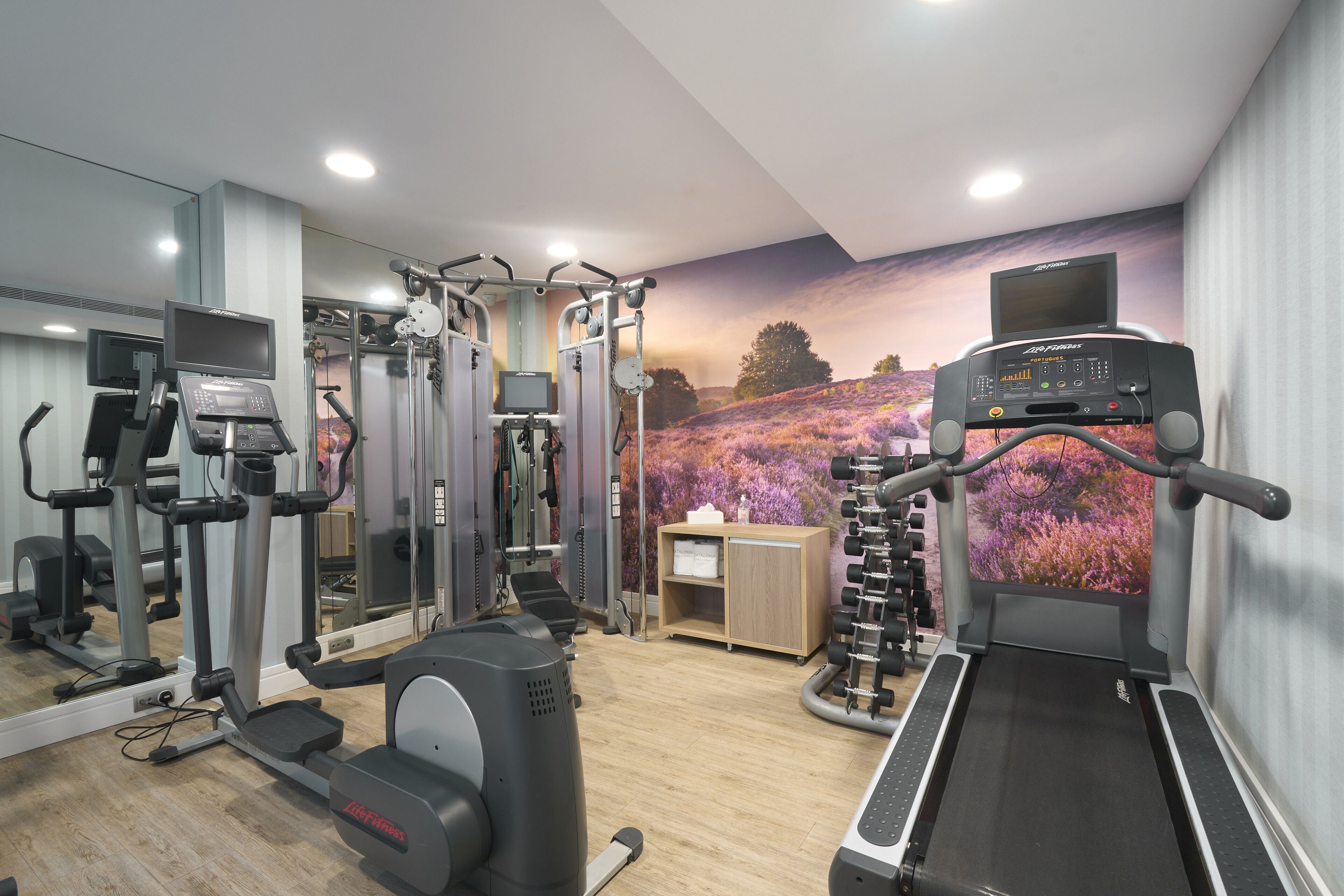 A gym with cardio machines, weightlifting equipment, and a mirrored wall.
