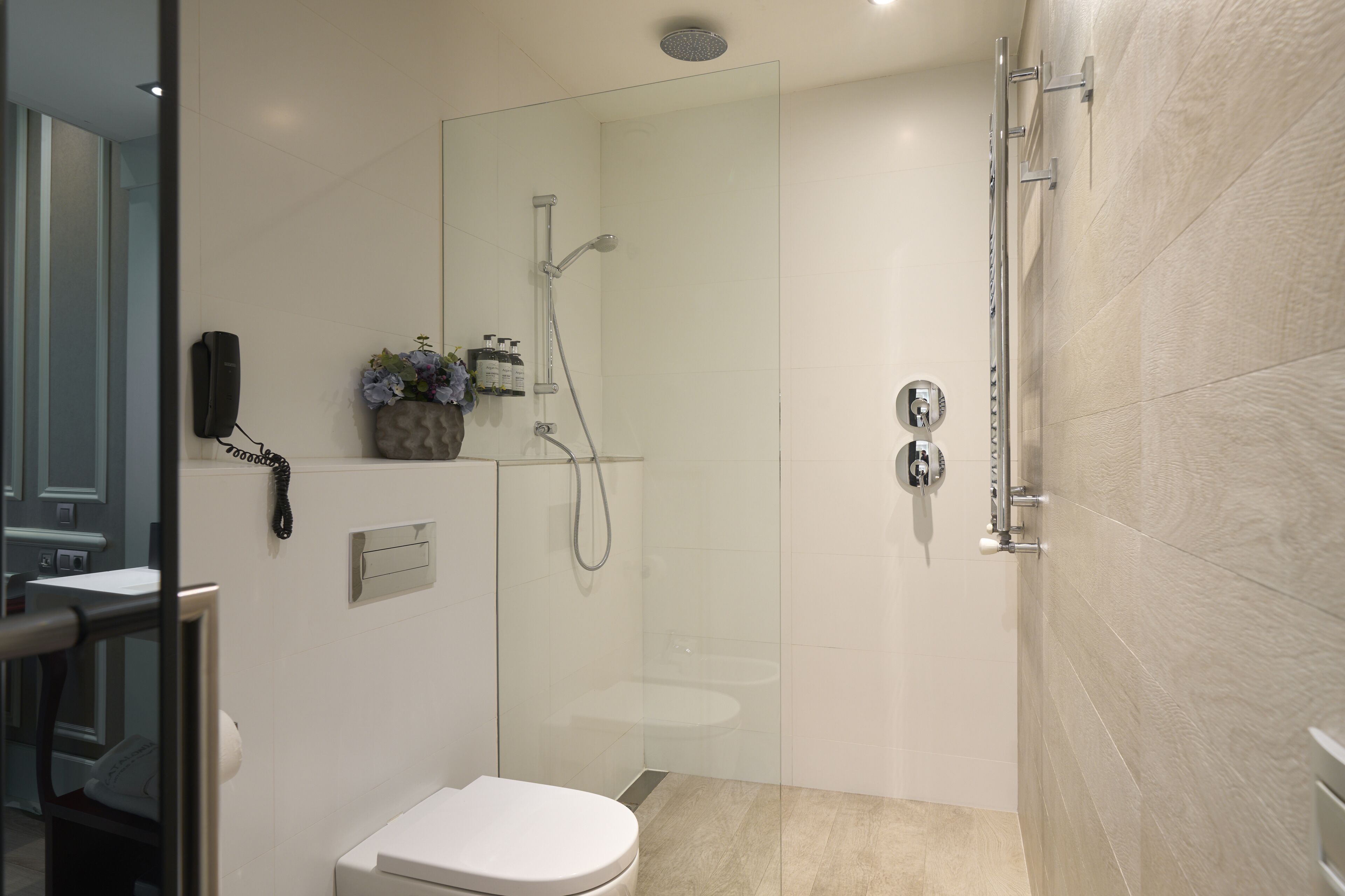 A modern bathroom with a glass-enclosed shower, a toilet, and a sink.