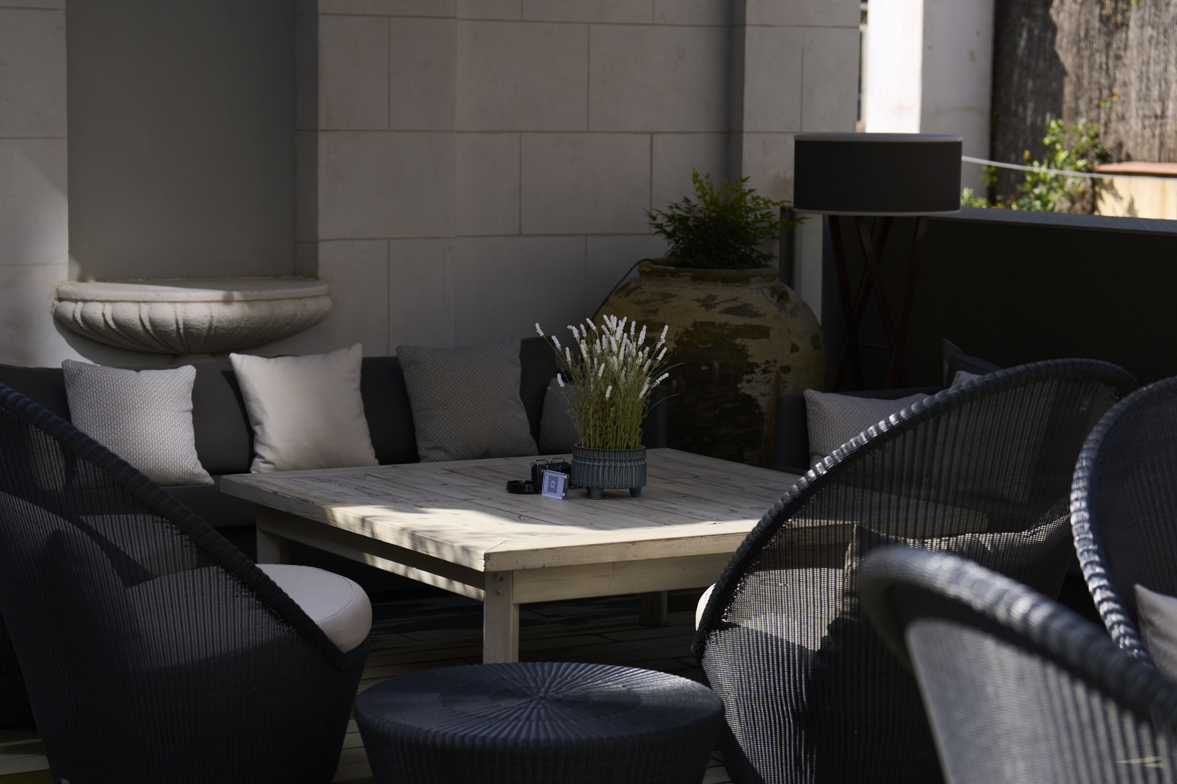 An outdoor seating area with a table and chairs, a potted plant, and a speaker.
