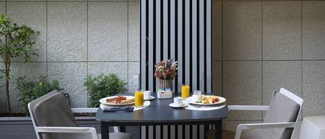 Una mesa de comedor con alimentos para el desayuno, sillas y un panel decorativo en la pared.
