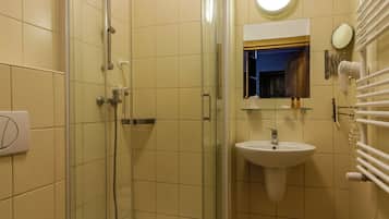 A bathroom with a glass-enclosed shower, a sink, a toilet, and a mirror.