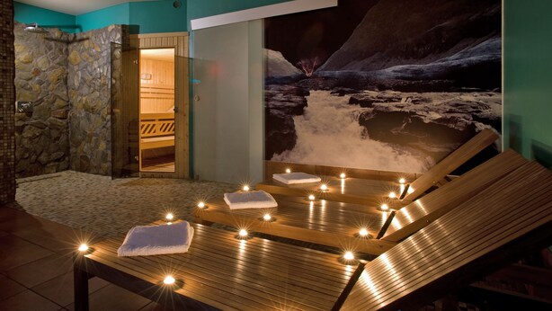 A spa area with a wooden massage table, towels, and candles. - Hotel Orle (Gdansk)