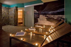 Zona de spa con camilla de masaje de madera, toallas y velas.