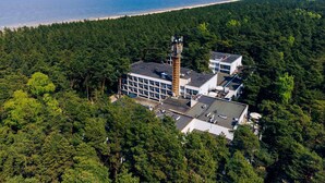 A building surrounded by dense forest with a beach in the background. - Hotel Orle (Gdansk)