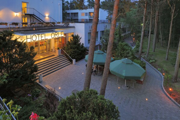 A hotel entrance with a staircase leading up to the lobby, surrounded by greenery and outdoor seating. - Hotel Orle (Gdansk)