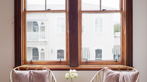 A room with two chairs facing a large window with a view of buildings. - The Martinborough Hotel (Martinborough)