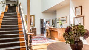 A spacious lobby with a grand staircase, a reception desk, and a large vase of flowers. - The Martinborough Hotel (Martinborough)