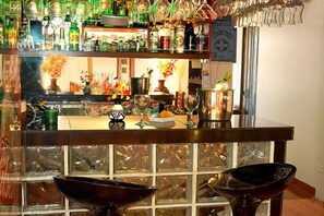 A bar area with shelves of bottles and glasses, a counter with a vase of flowers, and a decorative wall with a grid pattern. - Royal Inca Hotel (Lima)