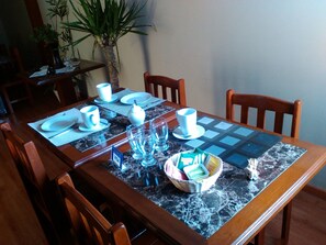 Una mesa de comedor servida con platos, tazas y un bol de salsas.