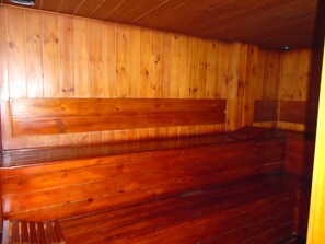 Interior de una cabaña de madera con un banco y unas escaleras.