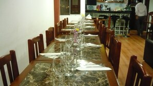 A long dining table set with multiple chairs, a marble top, and a bar area in the background. - Royal Inca Hotel (Lima)
